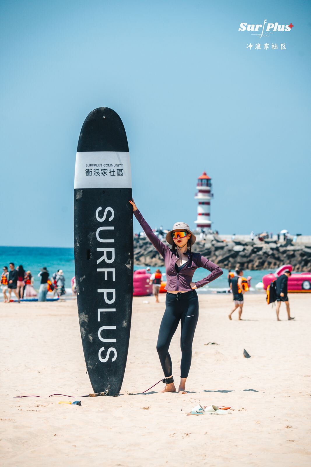 冲浪者与 SURFPLUS 冲浪板在海边灯塔前合影